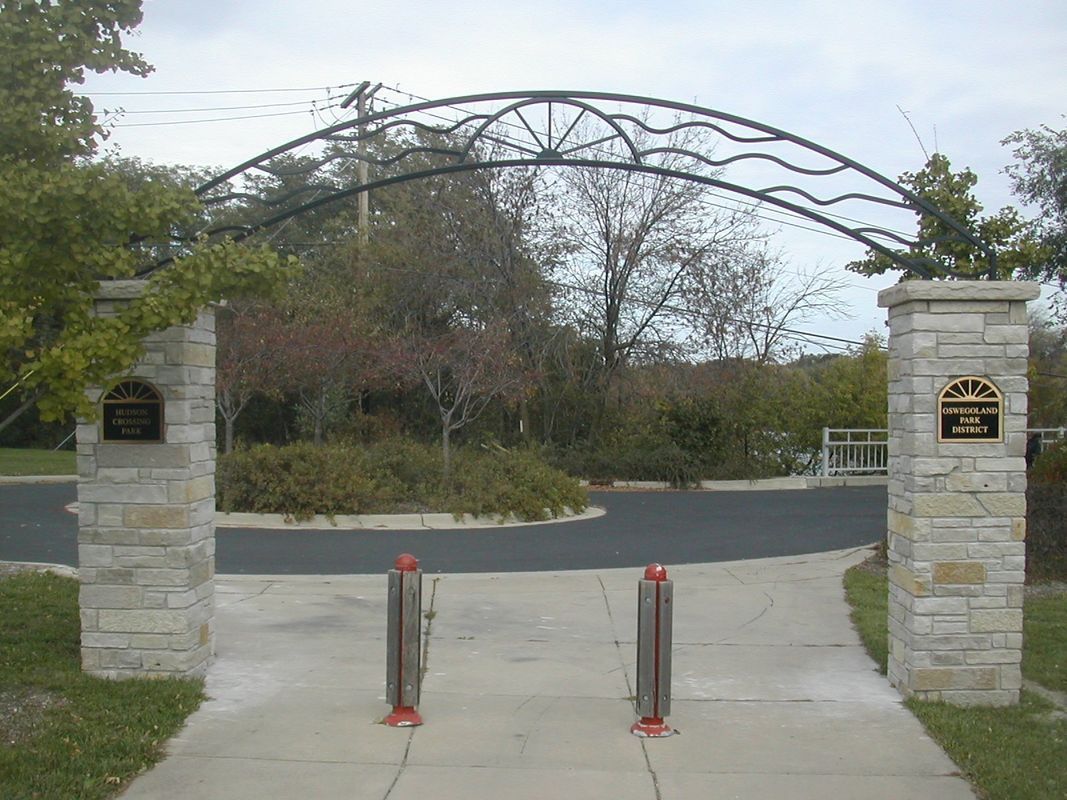 A stone archway leading to a park with trees in the background