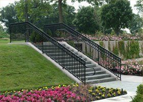 A set of stairs leading up to a garden with flowers and trees.