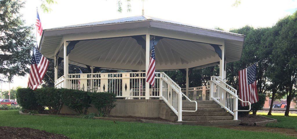 A gazebo in a park with american flags on it.