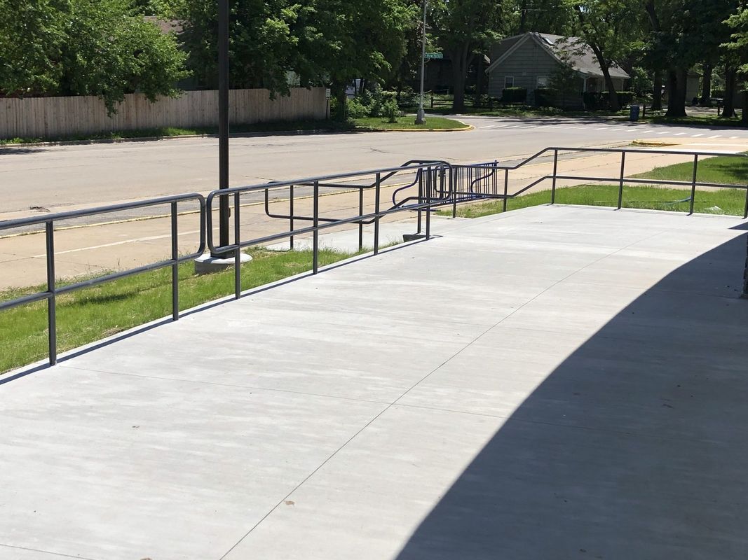 A concrete walkway with a metal railing on the side of it.