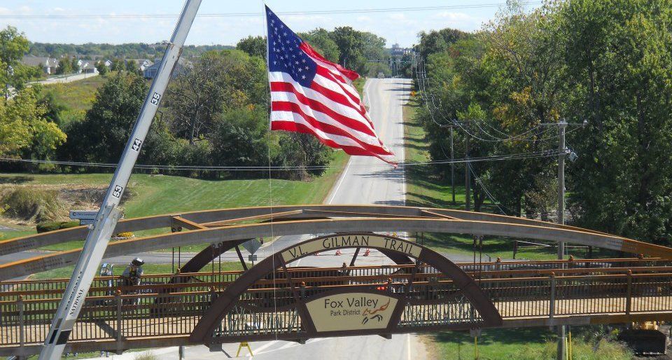An american flag is flying over a bridge over a road