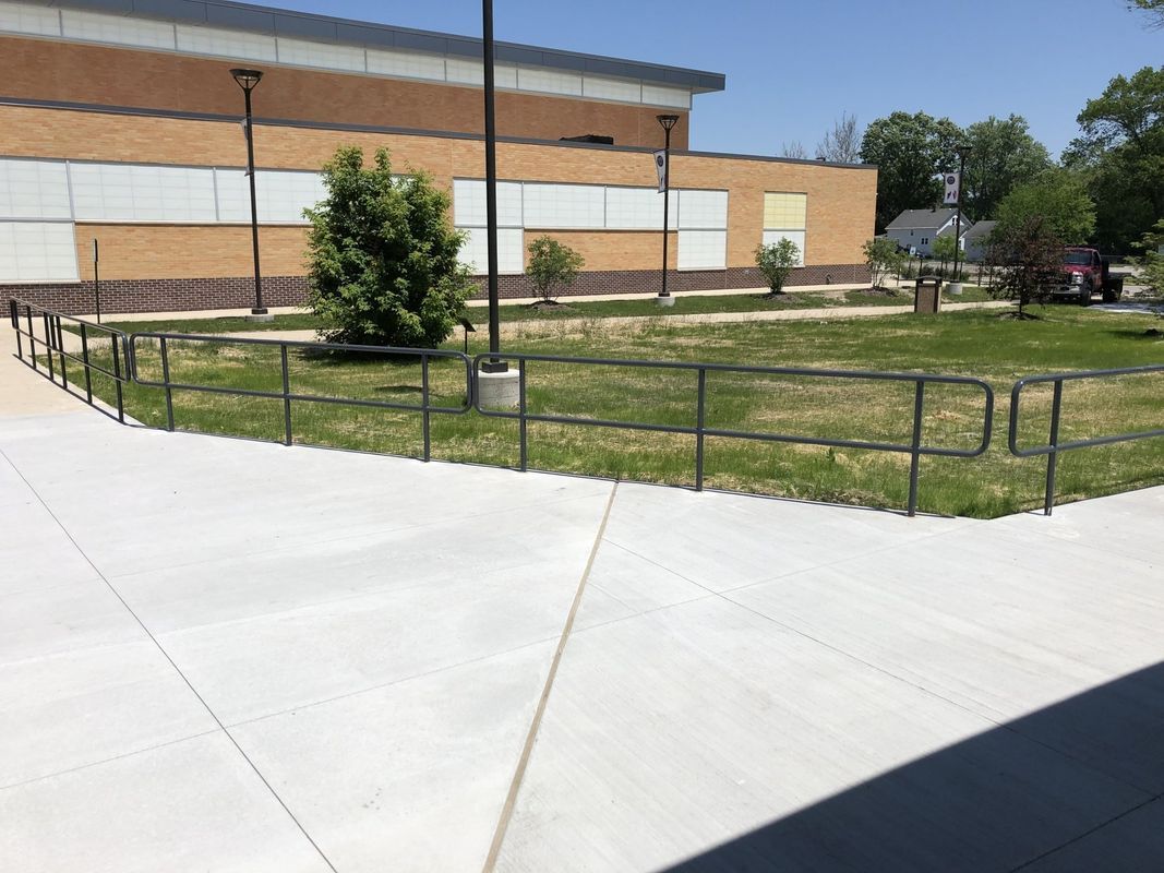 A fence surrounds a grassy area in front of a building.