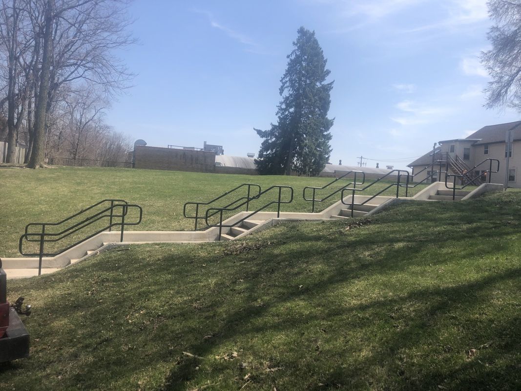 A row of stairs leading up to a grassy hill in a park.
