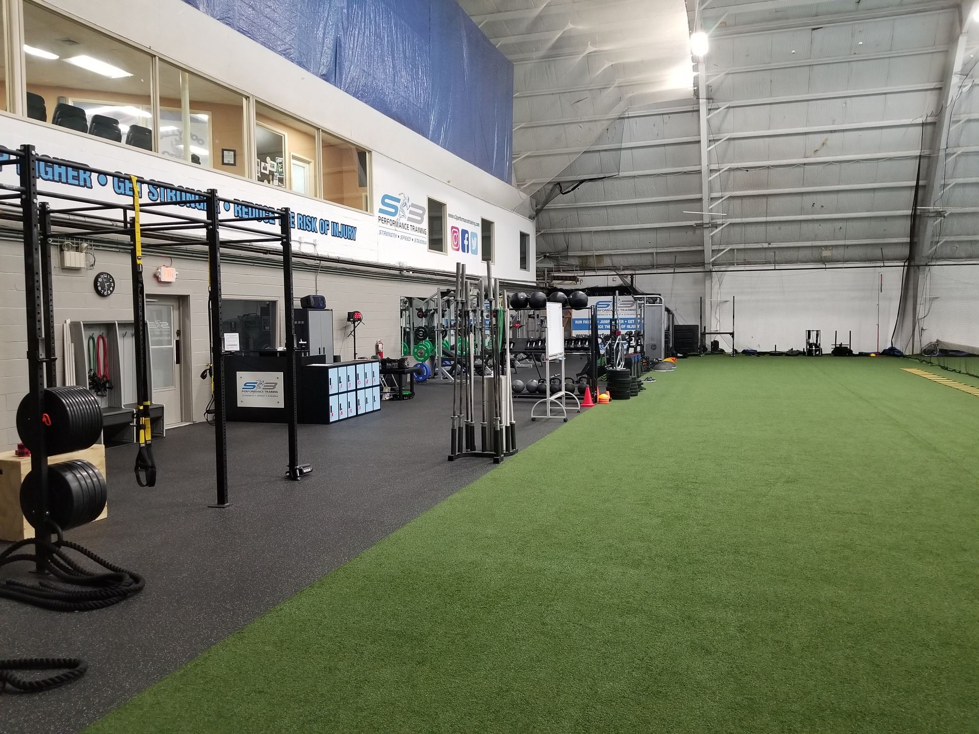 Indoor gym with artificial turf, exercise equipment, and blue wall.