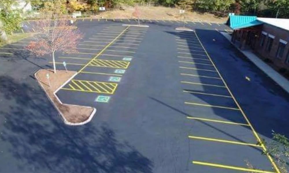 Asphalt parking lot with yellow parking space lines. Several handicap spaces are marked. Building on right side.