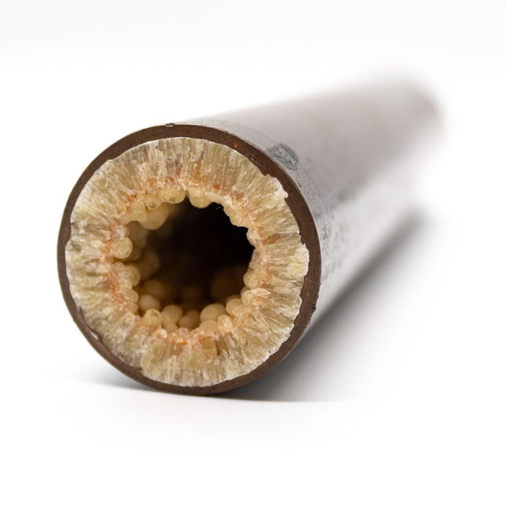 Close-up of a hollow metal pipe cross-section with rust-colored buildup inside on a white background.