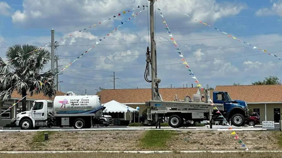 Utility trucks parked along a road at a construction site under a blue sky with pennant flags.