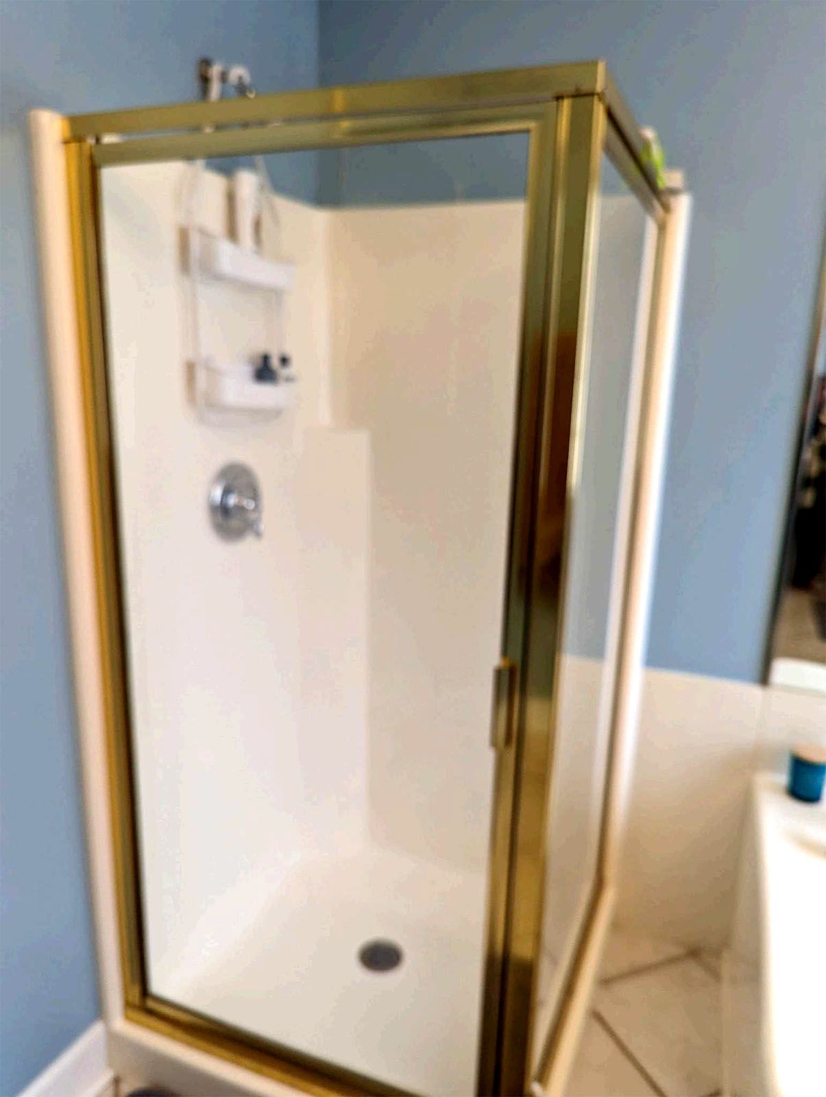 A shower stall with a gold frame in a bathroom