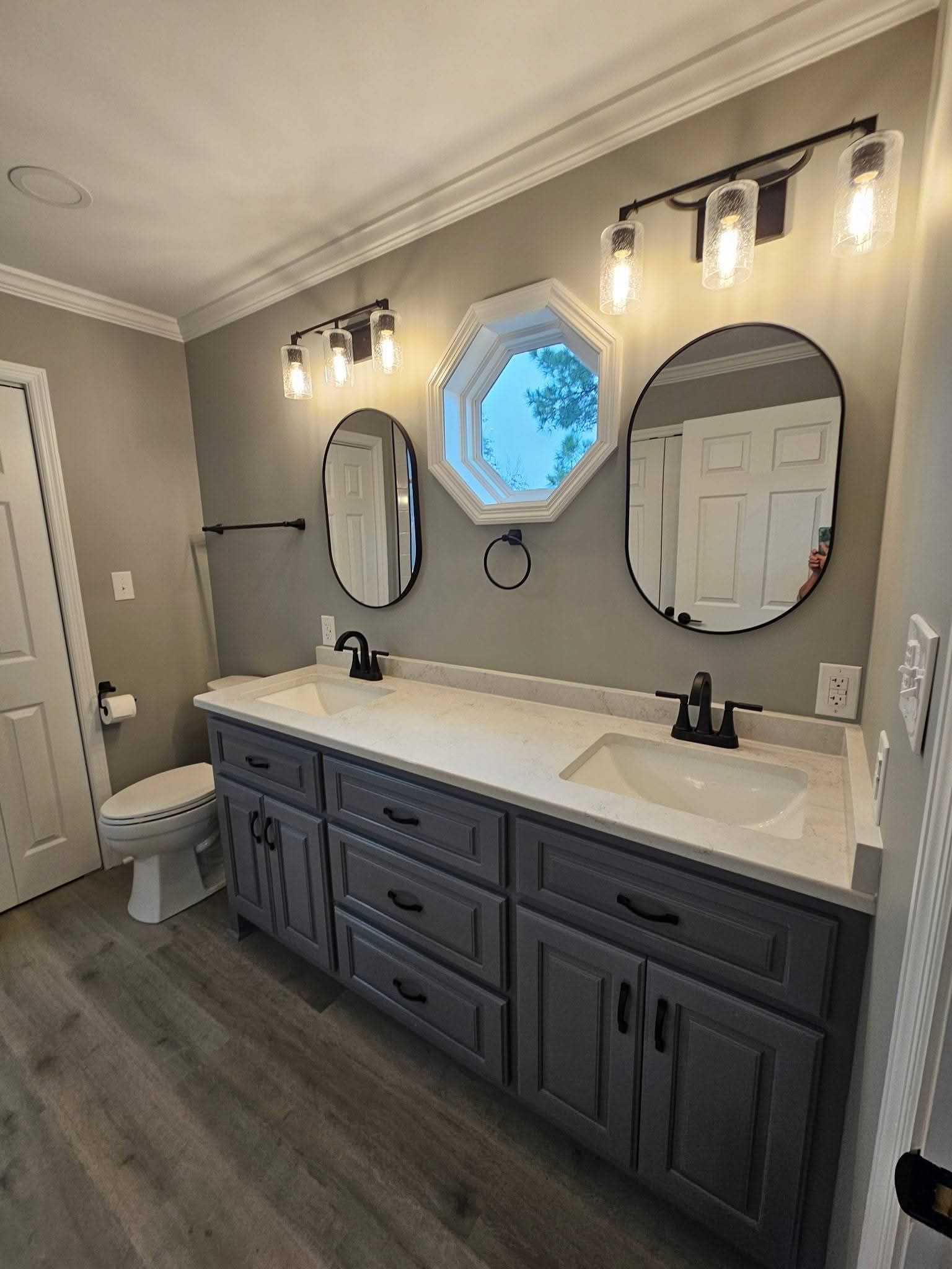 Gray and white bathroom with a double vanity, mirrors, and lighting fixtures.