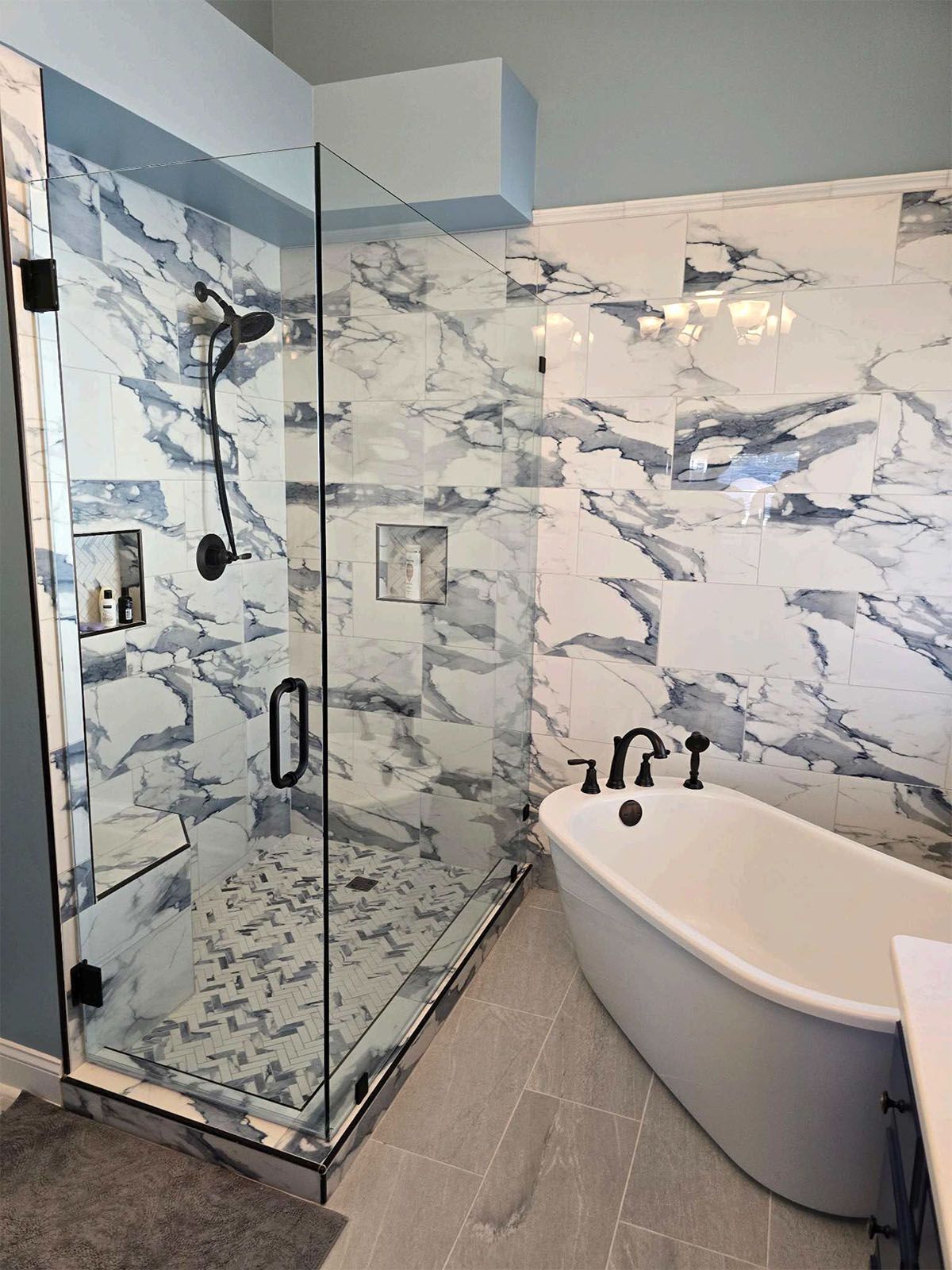 A newly remodeled bathroom with a bathtub, shower, and marble wall
