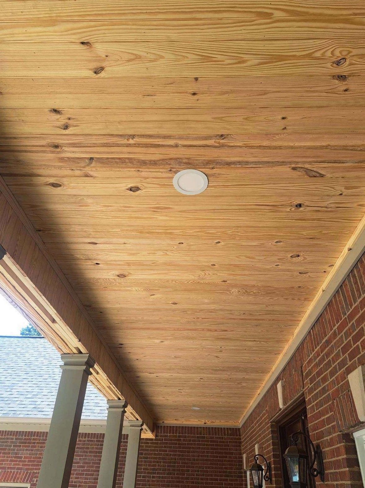 A porch with a wooden ceiling and a light on it.