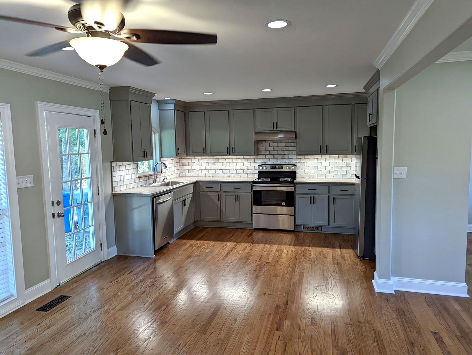 A kitchen with grey cabinets and hardwood floors