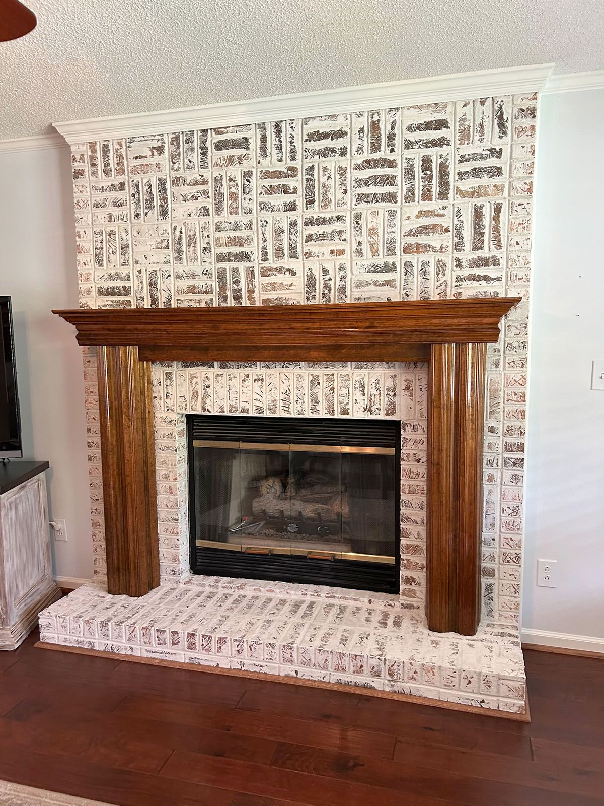 A living room with a fireplace and a wooden mantle