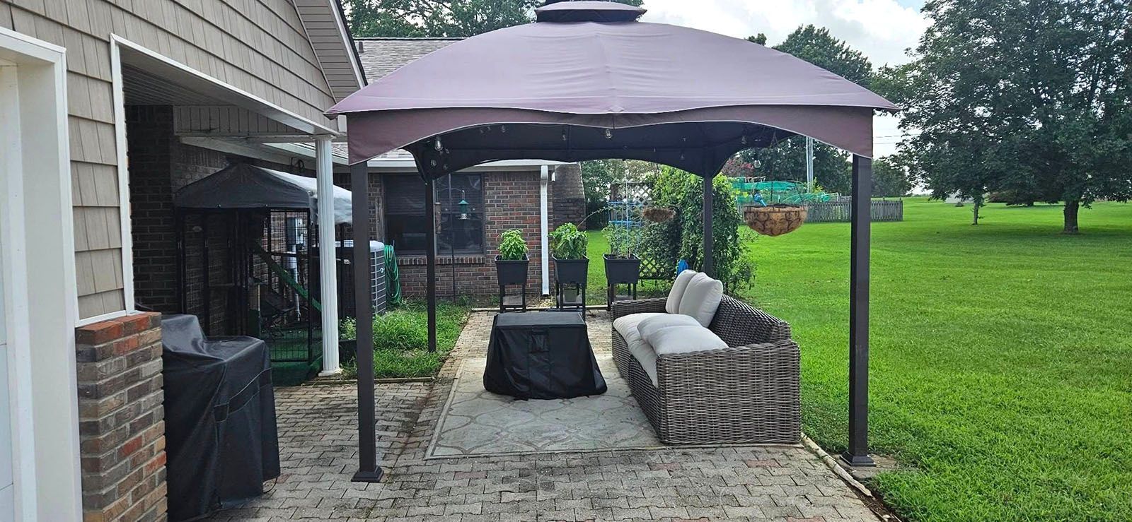 A pergola with a couch underneath it in the backyard of a house