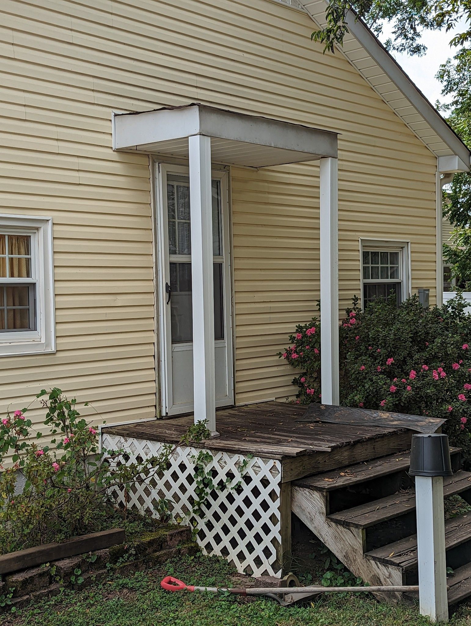A yellow house with a white porch and stairs