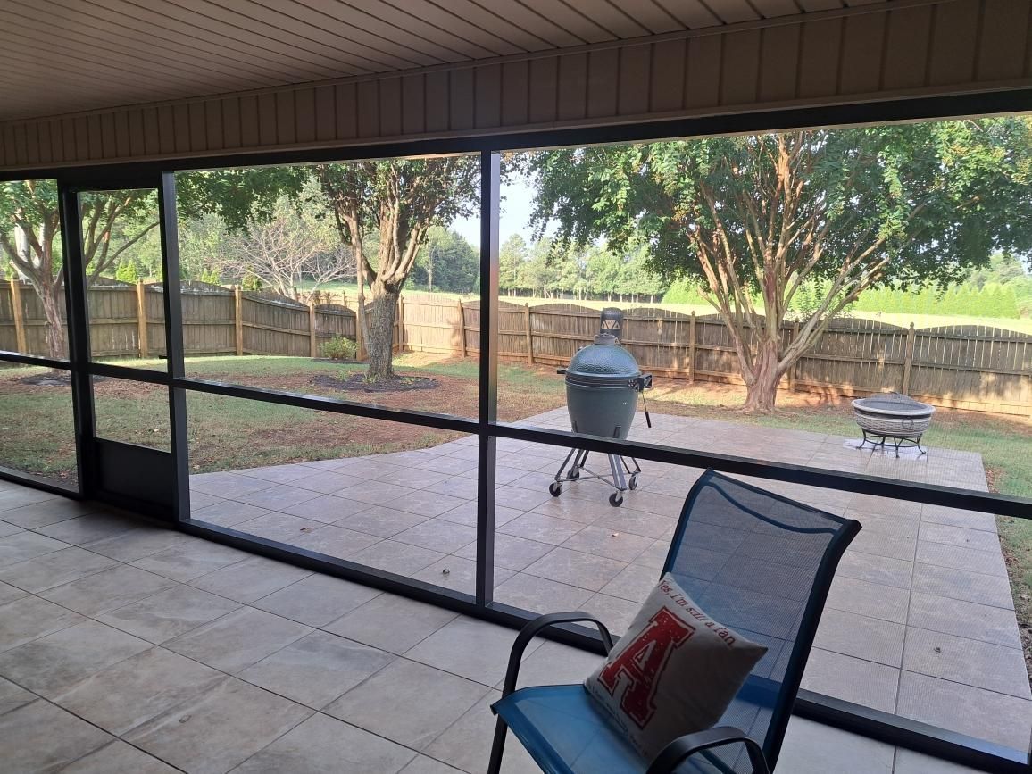 A screened in porch with a chair and a grill