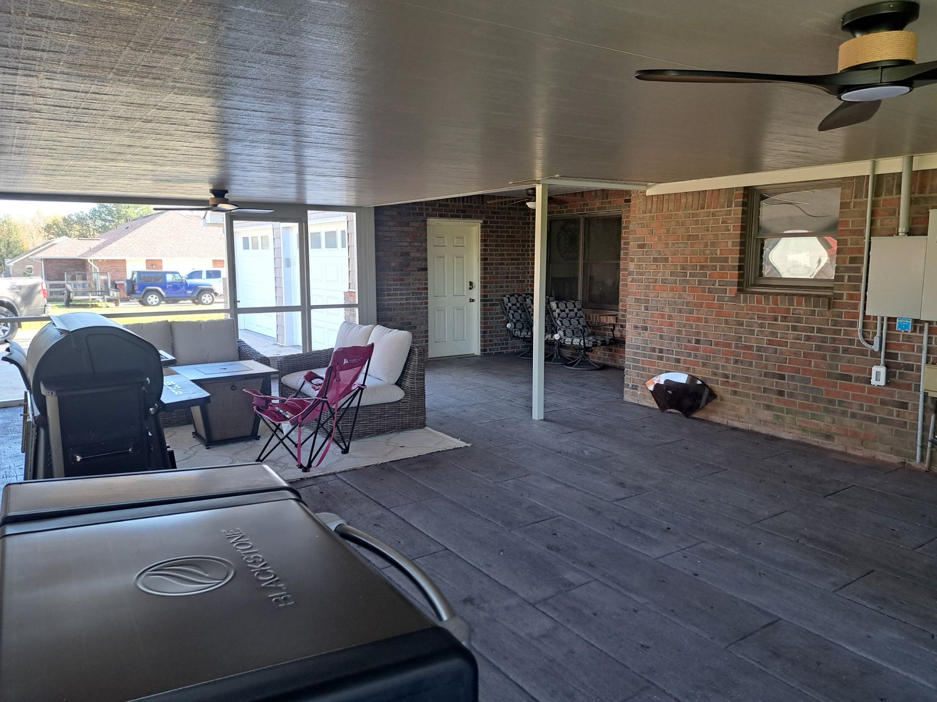 A living room with a grill, chairs, and a ceiling fan