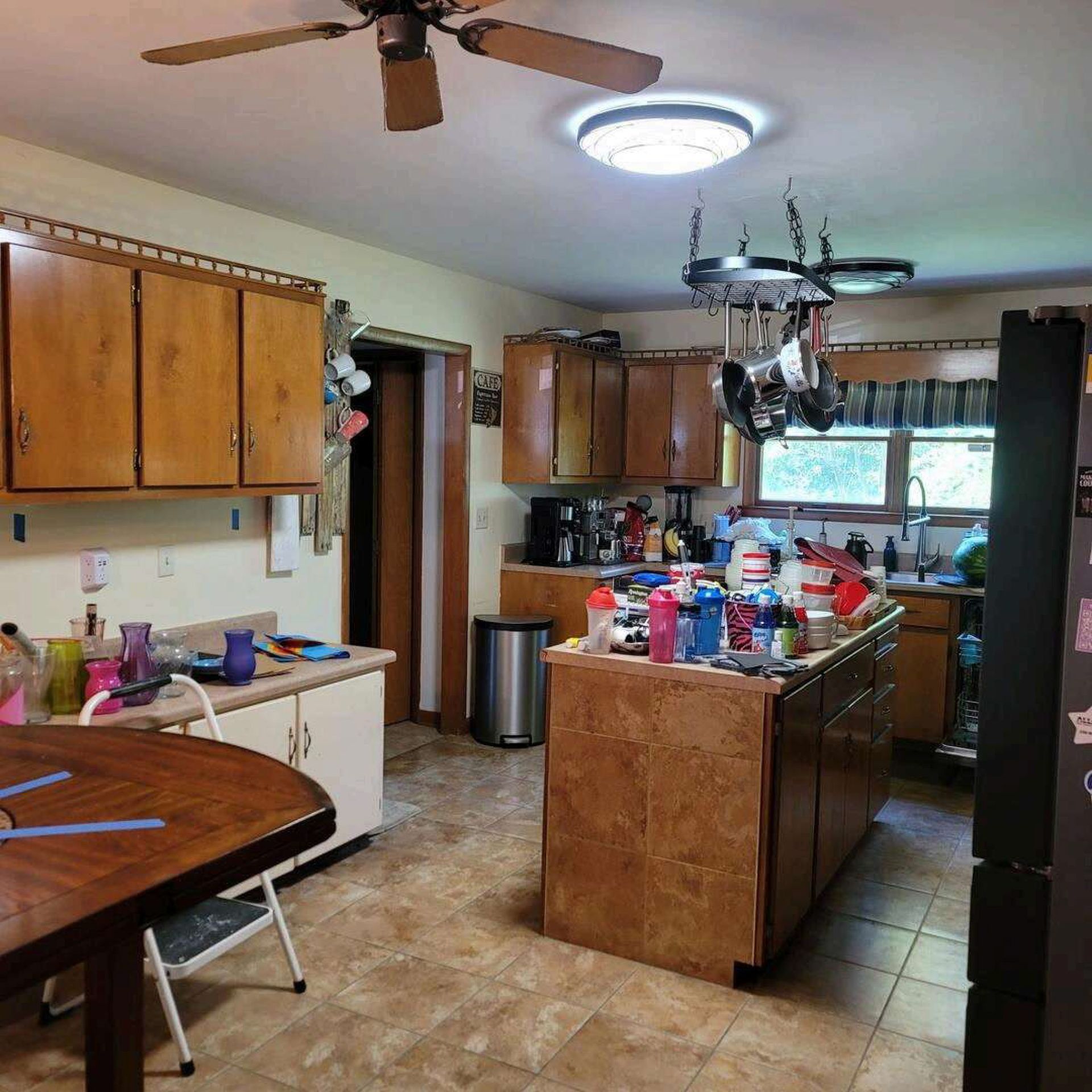 Kitchen with wooden cabinets, an island, a round table, and a black refrigerator.