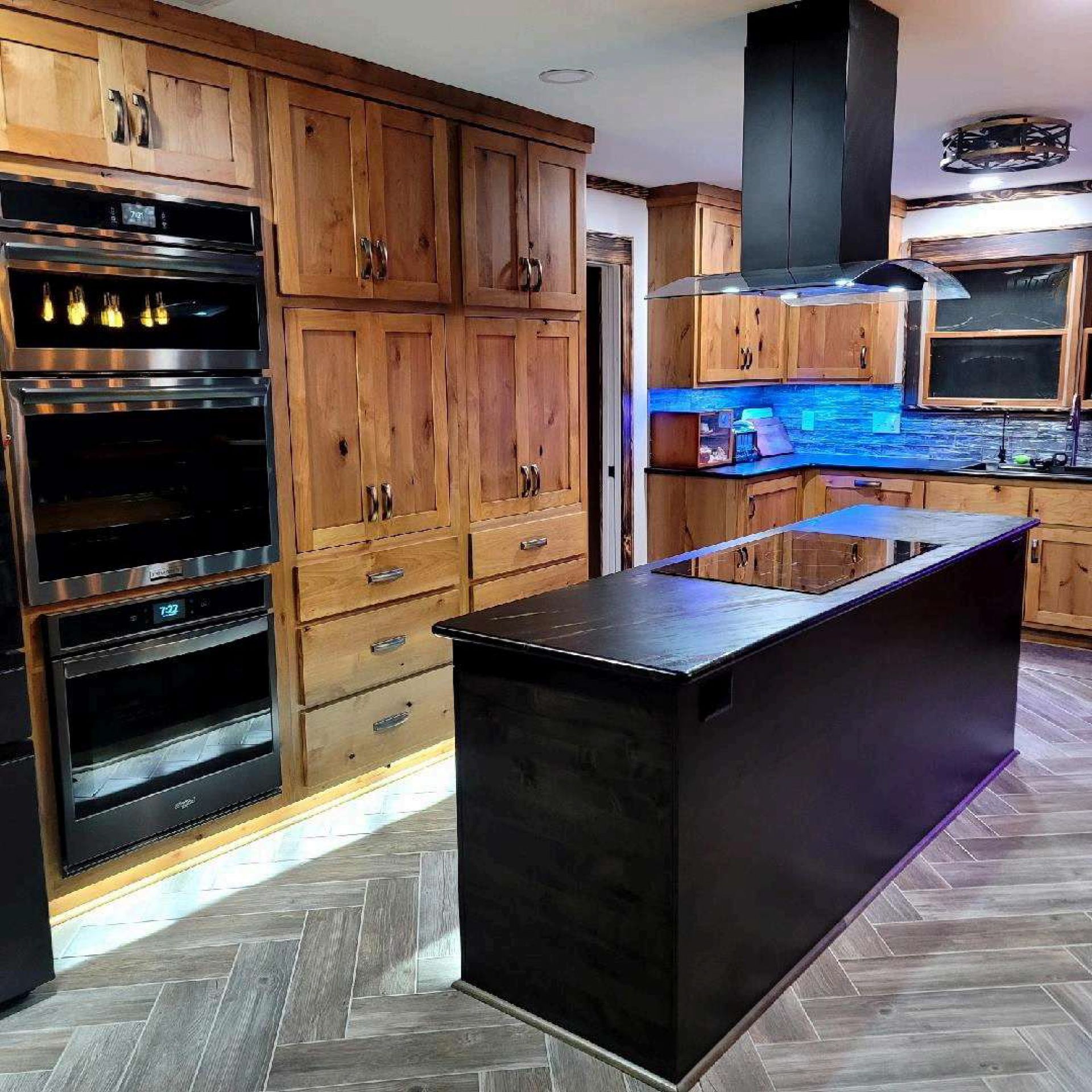 Kitchen with wood cabinets, a black island, and stainless steel appliances.
