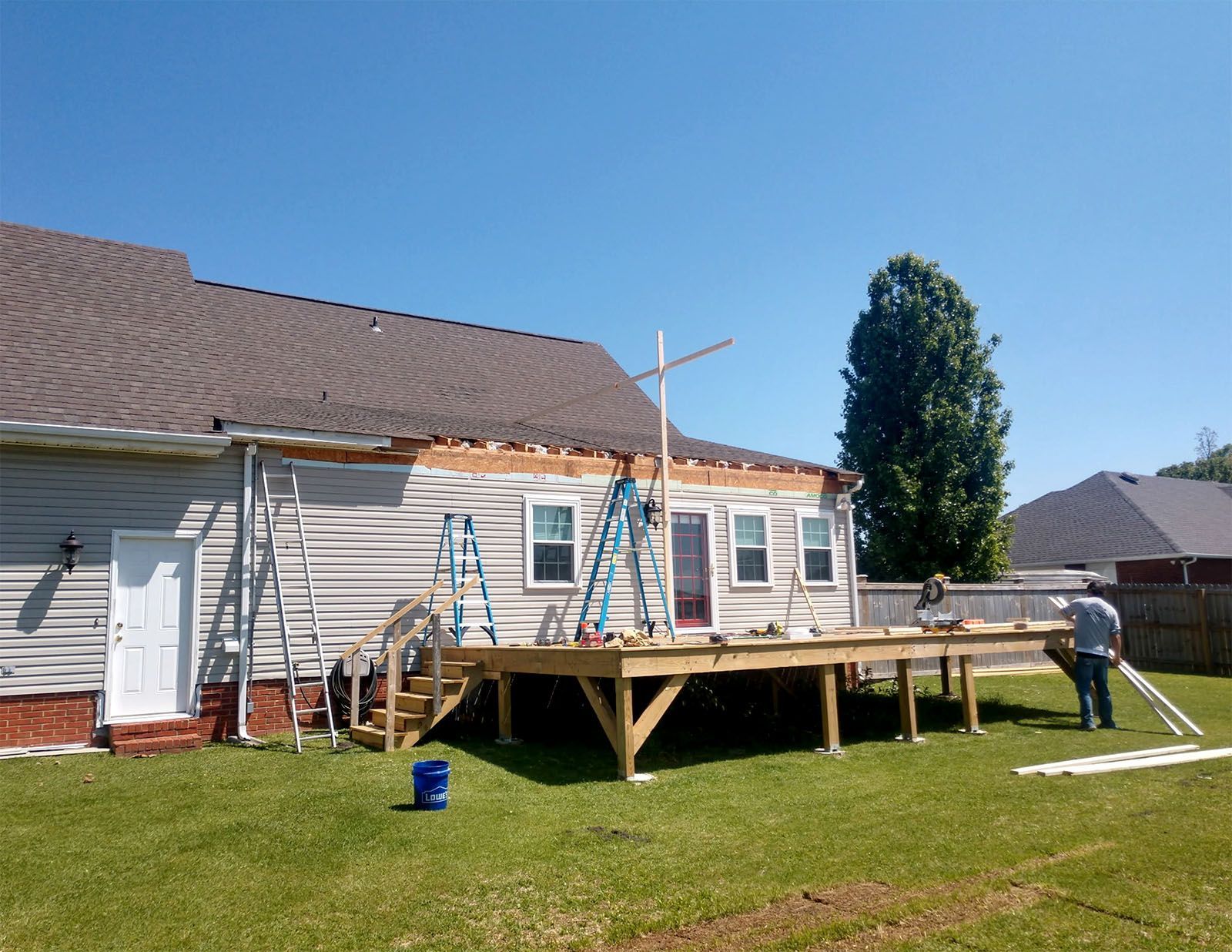 A man is working on a deck in front of a house