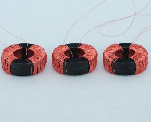 Three copper and black coils are sitting next to each other on a white surface.