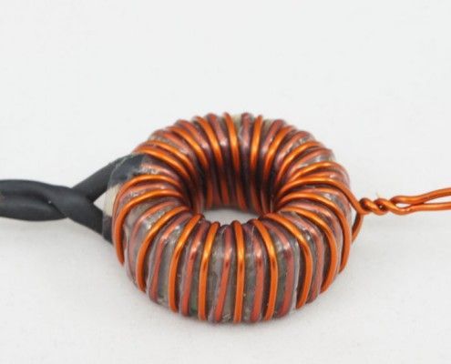 A close up of a copper wire coil on a white surface.