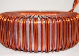A close up of a copper wire coil on a white surface.
