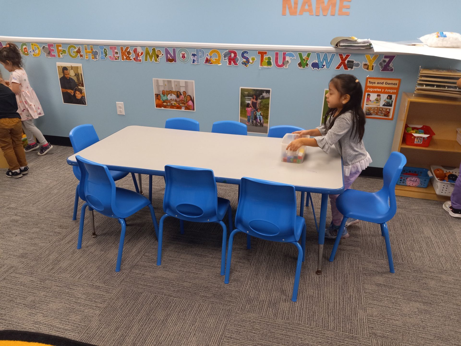Toddler standing next to a table with several chairs