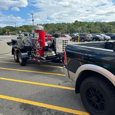 A truck with a trailer attached to it is parked in a parking lot.