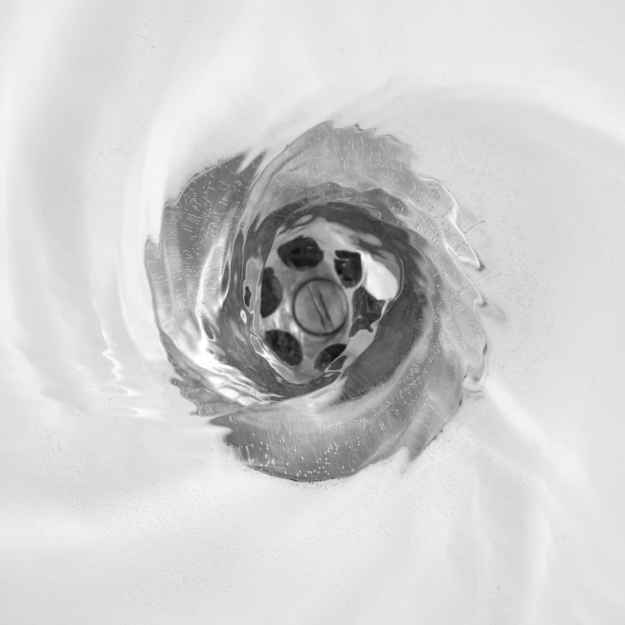 A close up of a sink drain with water running down it.