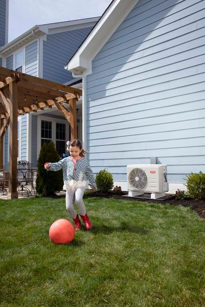 Girl plays with a ball near an outdoor HVAC unit on a sunny day.