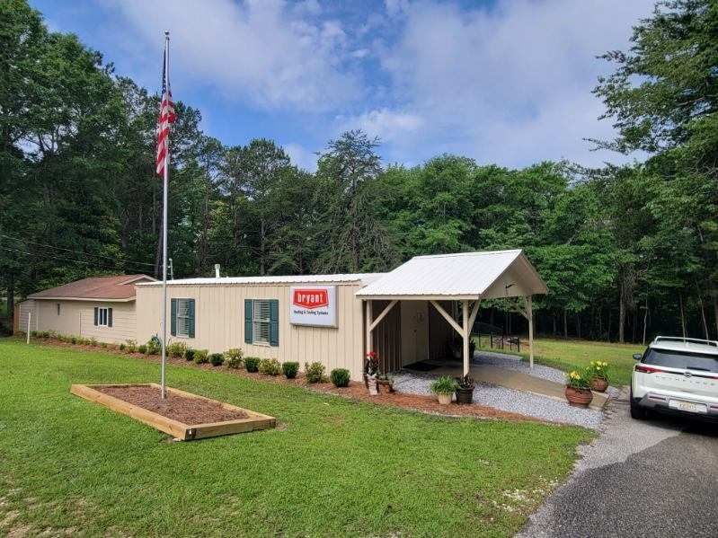 A one-story beige building with a white carport and an American flag in front.