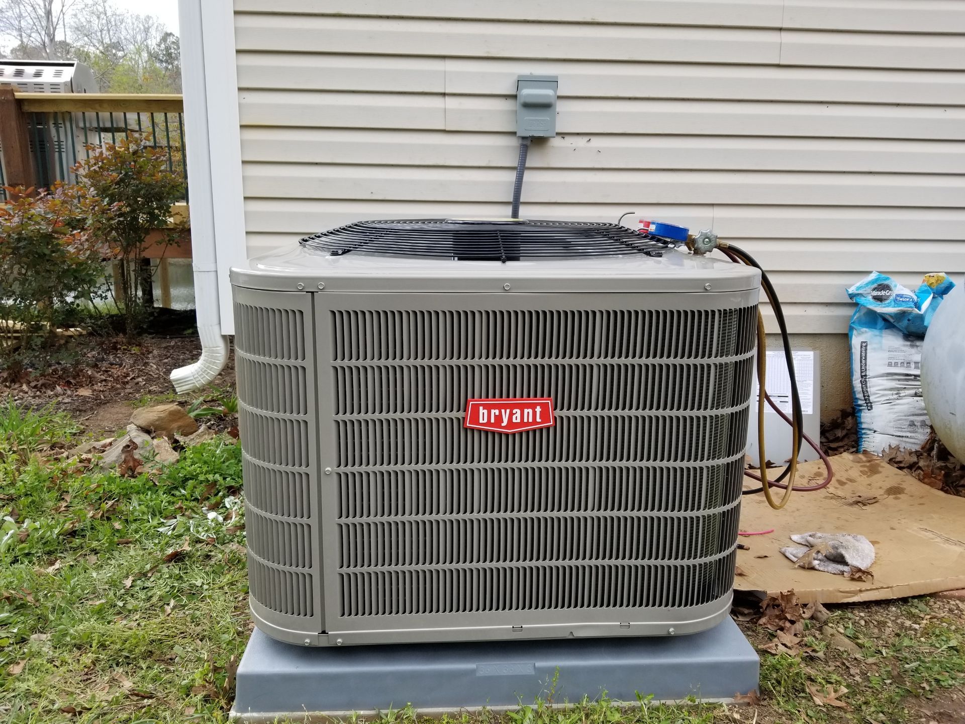 Bryant air conditioner unit outside a building. Gray with red logo, on a concrete pad.