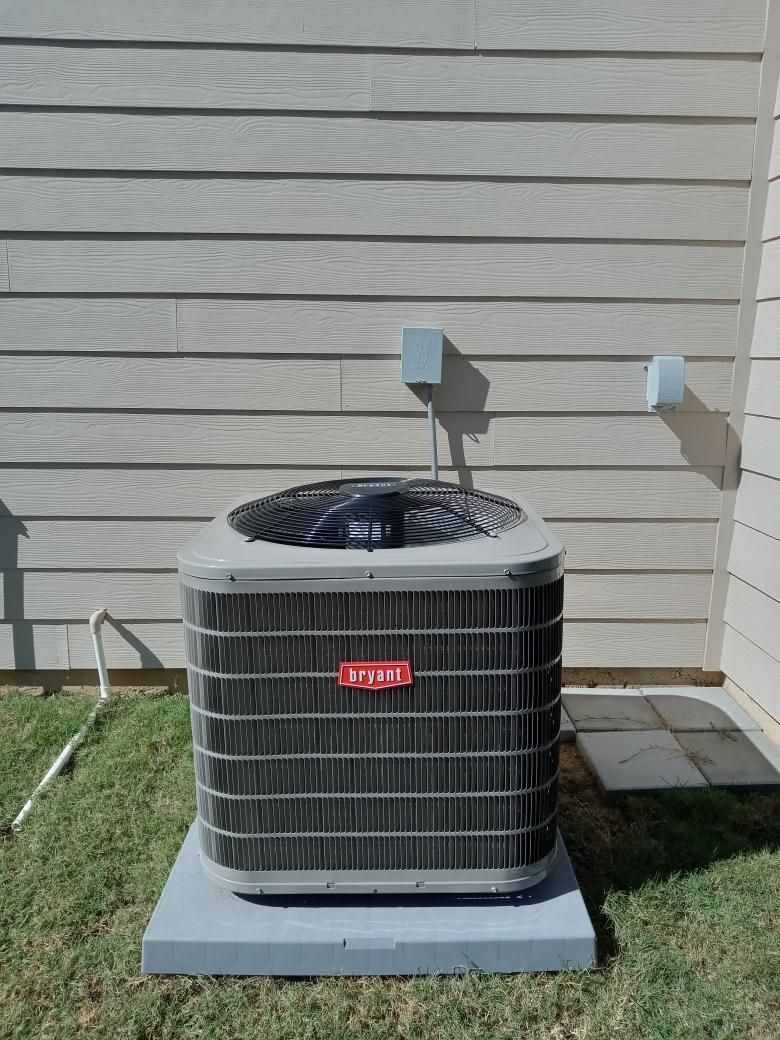 Goodman air conditioning unit on a concrete pad next to a beige siding wall.