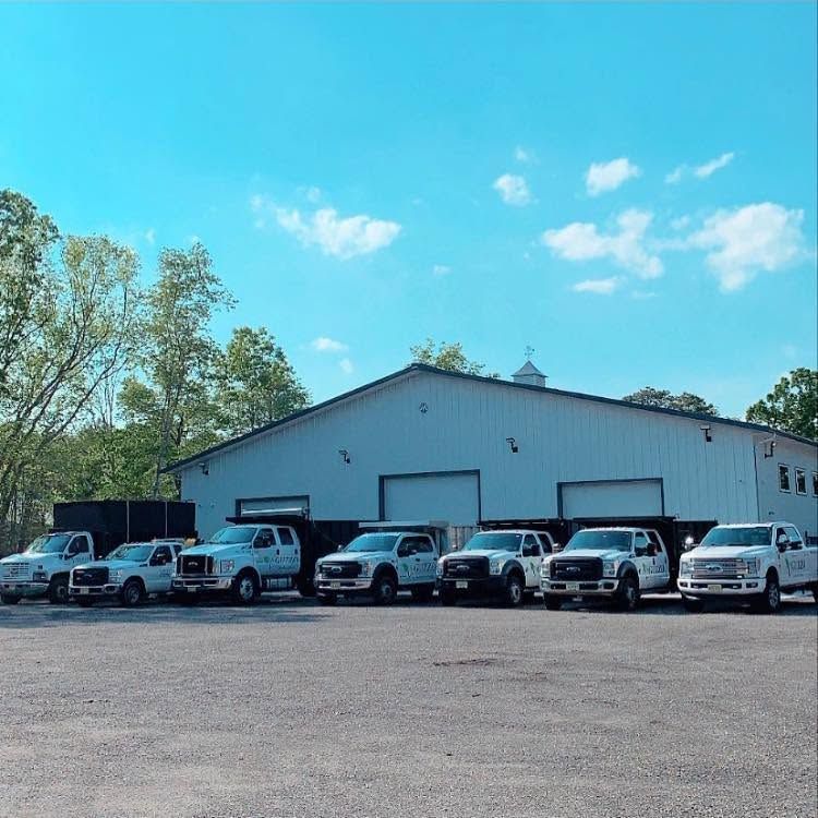 A row of parked white vans and SUVs in front of a gray building under a blue sky