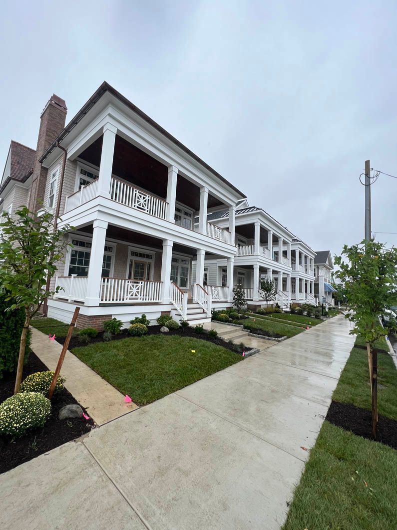 Row of white porch homes along a wet sidewalk on an overcast day