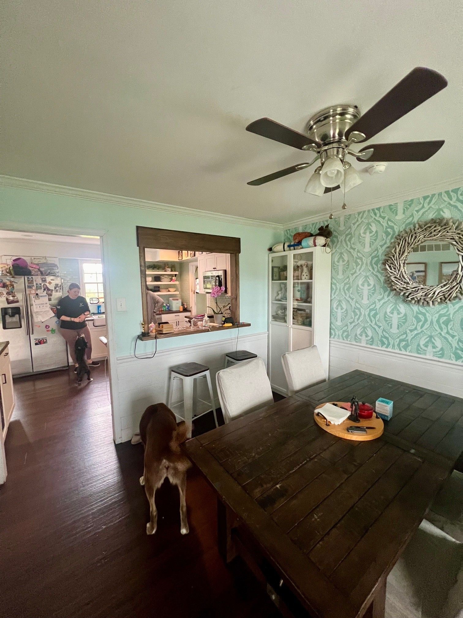 A dining room with a wooden table and chairs and a ceiling fan.