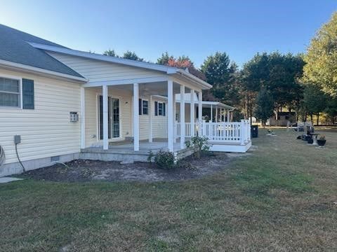 A white house with a porch and a lawn in front of it.
