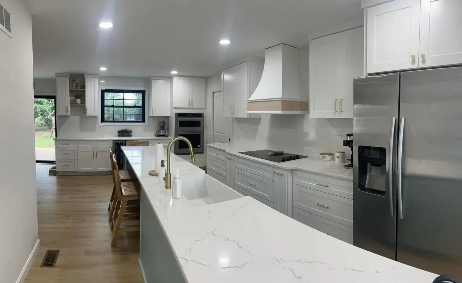Bright white modern kitchen with island, stainless appliances, and hardwood floors