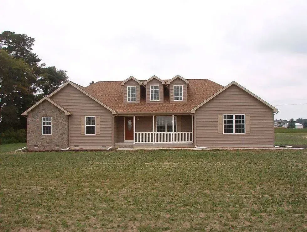 Single-story beige house with a red roof and front porch on a grassy lot