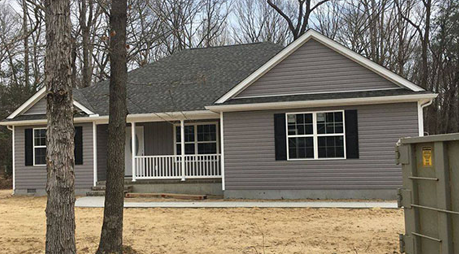 A house with a porch and a dumpster in front of it.