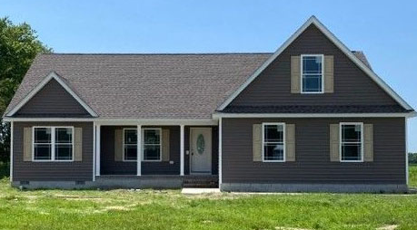 A brown house with a gray roof is sitting on top of a lush green field.