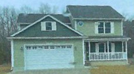 A green house with a white garage door and a porch.