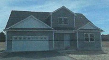 A picture of a house with a garage and a blue sky in the background.