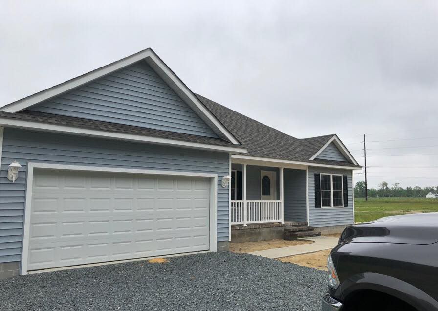 A black truck is parked in front of a blue house