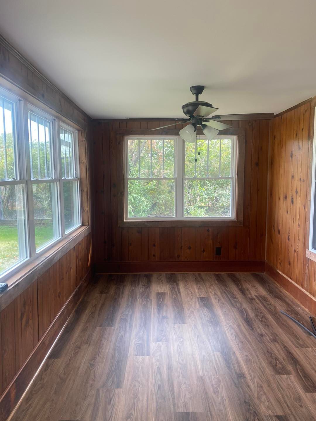 An empty room with hardwood floors and a ceiling fan.