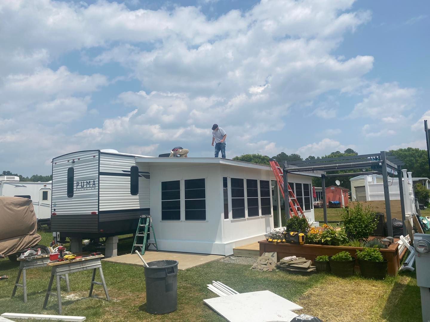 A man is standing on the roof of a mobile home.