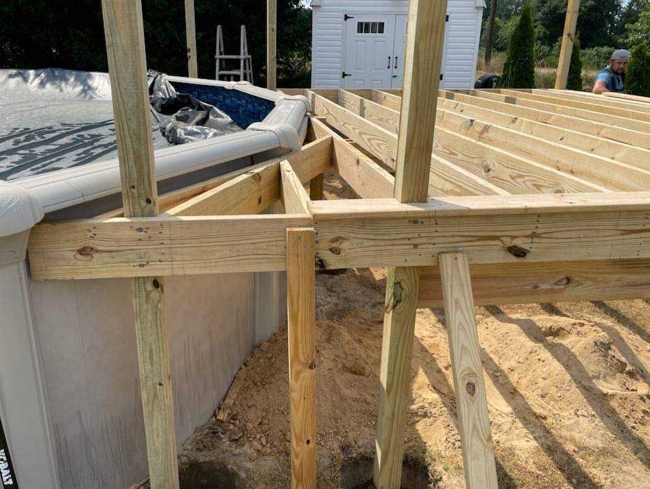 A wooden deck is being built around a pool.