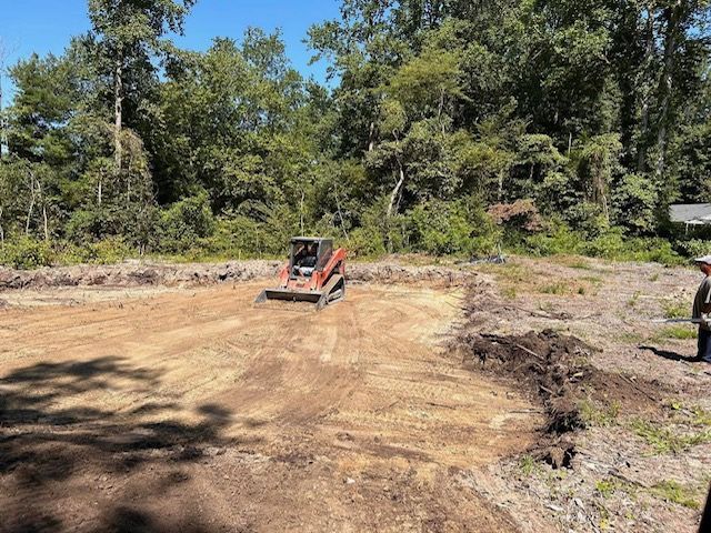 A bulldozer is moving dirt in a field with trees in the background.