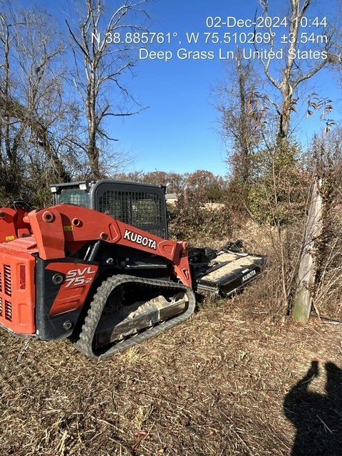 A red and black tractor is parked in a field.